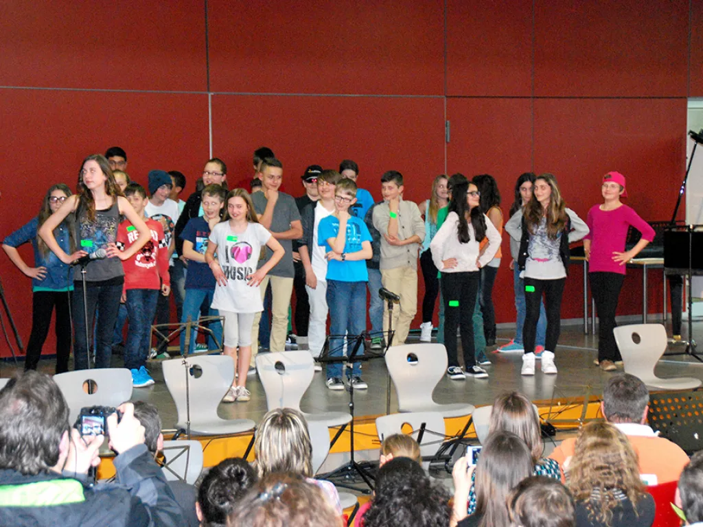 Gruppe steht singend vor der roten Wand.